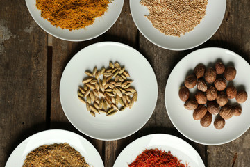 Different spices on plates, on old wooden table