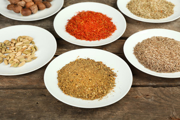 Different spices on plates, on old wooden table