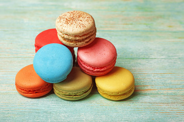 Tasty colorful macaroons on color wooden background