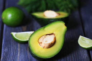 Sliced avocado with lime and herb on wooden table, closeup