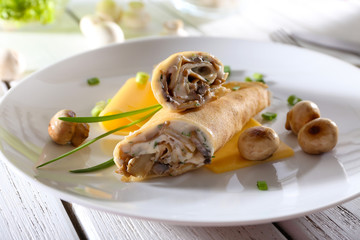 Pancakes with cream and mushrooms on wooden table, closeup