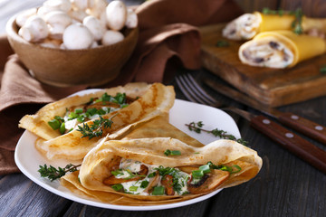Pancakes with creamy mushrooms on wooden table, closeup