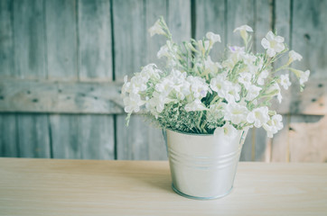 Vintage style White flowers stainless pot on wooden background,