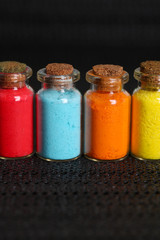 Bottles with colorful dry pigments on dark background
