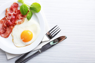 Bacon and eggs on color wooden table background