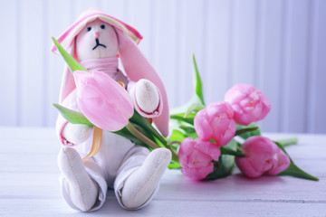 Beautiful pink tulips with toy on wooden background