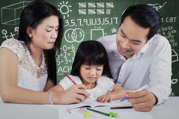 Little girl studying with parents at class