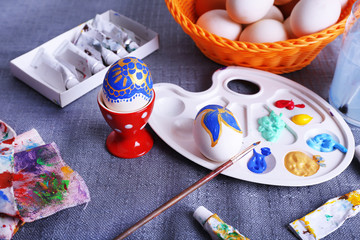 Painting Easter eggs on colorful tablecloth background