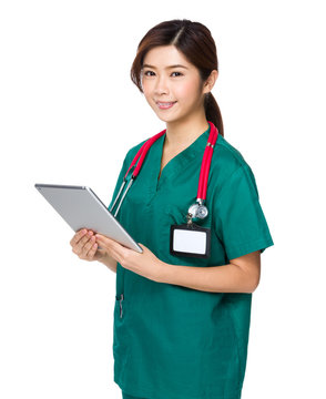 Young woman doctor in scrubs using tablet computer