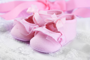 Fototapeta na wymiar Pink baby boots on cloth close-up