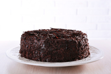 Tasty chocolate cake on table on brick wall background