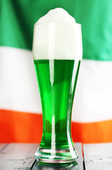Glass of green beer on flag background