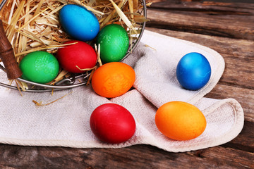 Easter eggs in basket on vintage wooden planks background