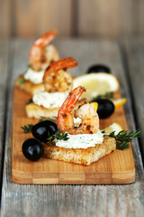 Appetizer canape with shrimp and olives on wooden background