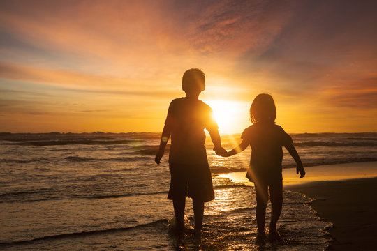 Two children holding hands at beach