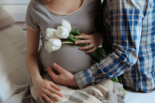 Fototapeta Young pregnant woman sitting with husband and holding flowers