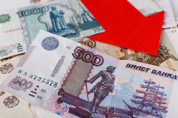 Red arrow on Russian money as depreciation of currency, closeup