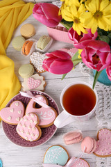 Composition of spring flowers, tea and cookies on table