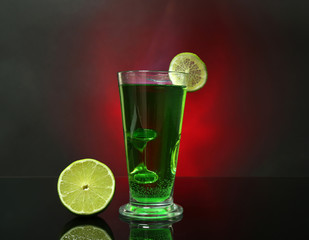 Flaming green cocktail on colorful background