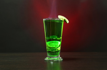 Flaming green cocktail on colorful background