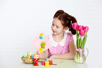 Fototapeta na wymiar Cute girl with greeting card and decorated Easter eggs,