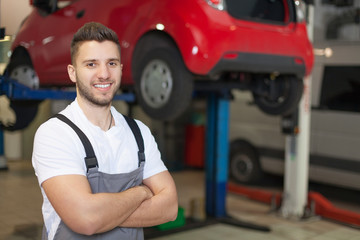 Smiling mechanic posing in auto repair shop - obrazy, fototapety, plakaty