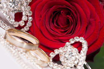 rote Rose und kleine Herzen mit zwei Eheringen