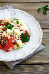 Salad with couscous and fresh vegetables on the white plate