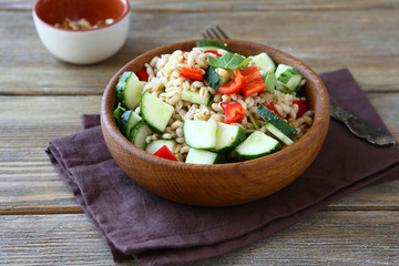 Pearl barley salad with vegetables in a wooden bowl