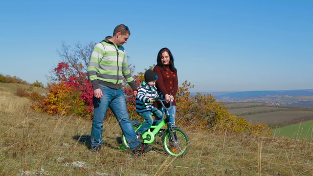 Happy Young Family With a Child Walking In Autumn Meadow
