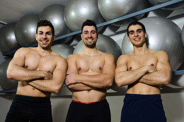 Fototapeta na wymiar Three strong men posing at gym