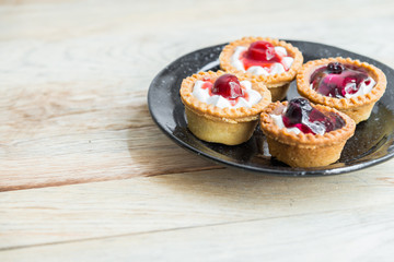 Strawberry and Blueberry tart in black plate on wooden floor