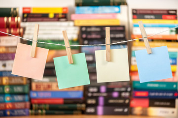 clear post it on string attached with pegs with books blurred