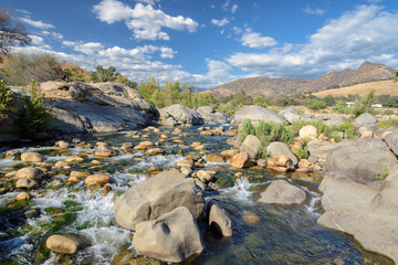 Mountains rapid river withy stones and plants in California county