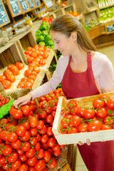 Shop worker carrying a crate of tomatoes