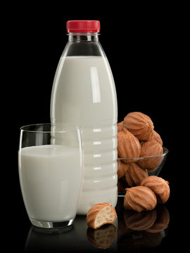 Plastic bottle, glass with milk and a vase with doughnuts