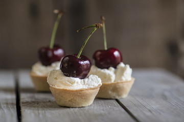 Cherry tartlets on rustic kitchen wooden background