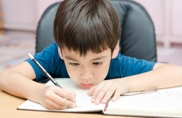 Little boy writing homework in the room