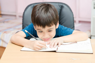 Naklejka premium Little boy writing and thinking homework