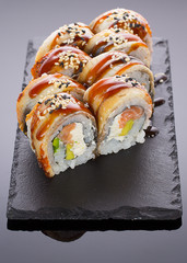 Eel sushi on a stone plate over black background