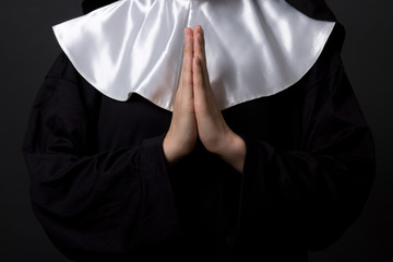 religion concept - hands of woman nun praying over grey