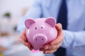 Businessman holding piggy box ,standing in office