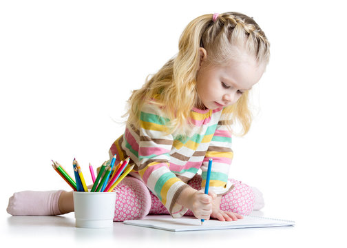 Cheerful child girl drawing with pencils in preschool