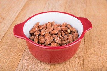 Almonds in bowl on wooden background