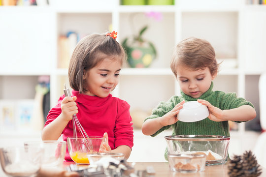 Cute little brother and sister preparing a dough