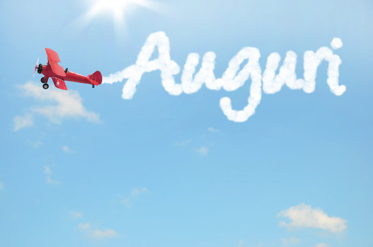 biplano che scrive auguri nel cielo