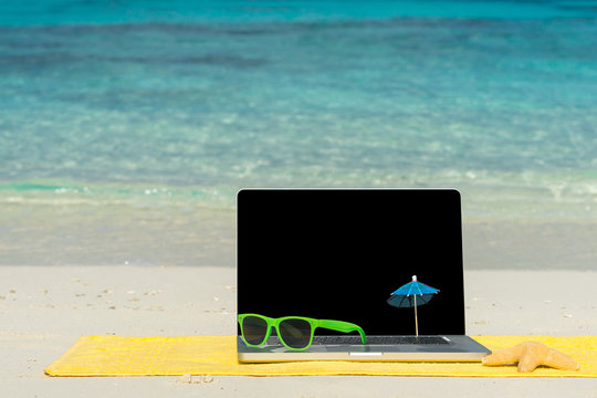 Computer notebook on beach - business travel background