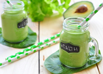 Green vegetable smoothie isolated on wood background
