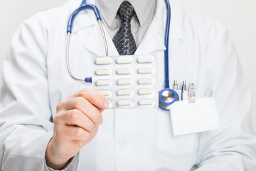 Doctor holdling pills in hand - studio shot