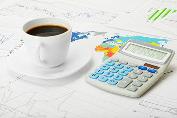 Coffee cup over world map and financial charts